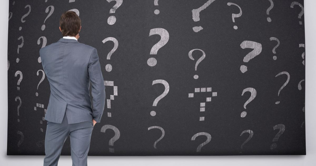 rear view businessman looking at question marks on blackboard