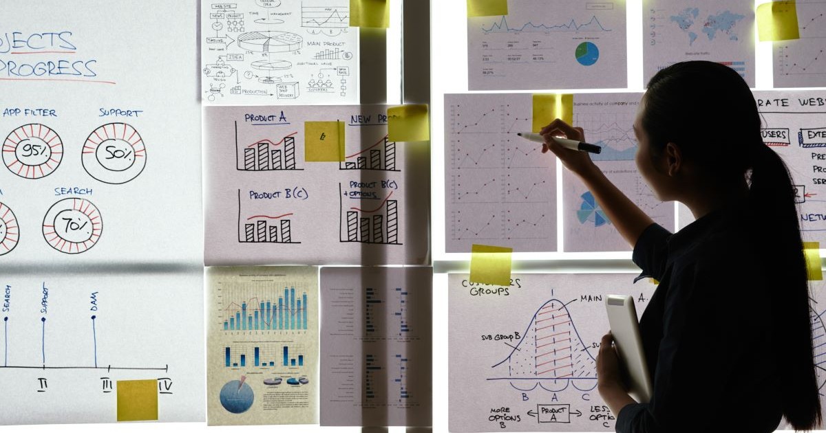 woman standing at office glass background looking at smart goals and graphs